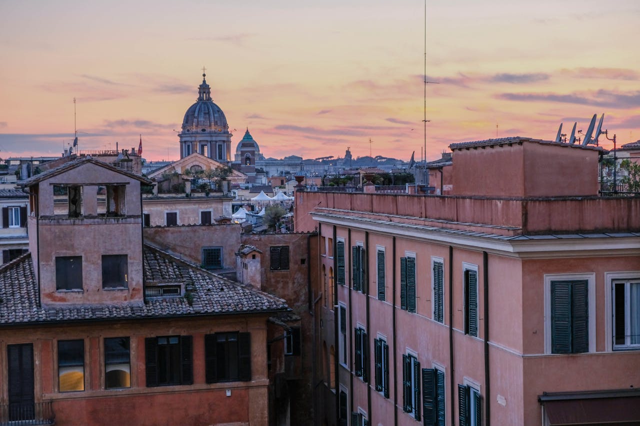 Breathtaking rooftop view over Rome with domes and historic architecture at sunset.